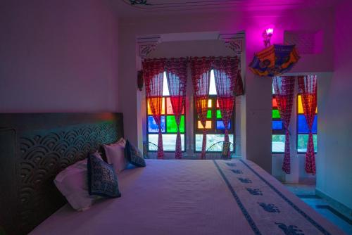 a bedroom with a bed with stained glass windows at Soham Haveli Udaipur in Udaipur