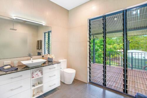 a bathroom with a sink and a toilet and a window at Golden Sands Retreat Beach House in Wagait Beach