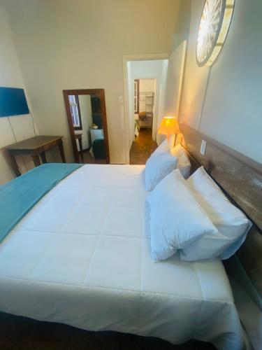 a large white bed in a bedroom with a lamp at POUSADA CHARLOTTE in Tiradentes