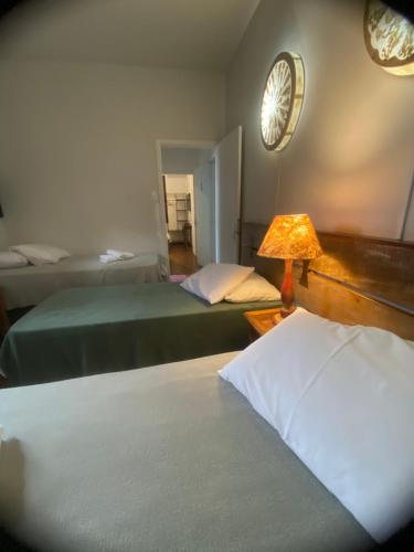 a bedroom with two beds and a lamp and a mirror at POUSADA CHARLOTTE in Tiradentes