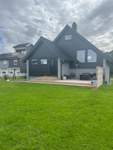 a large house with a green lawn in front of it at Lykkja - Beautiful Waterfront House in Viggja