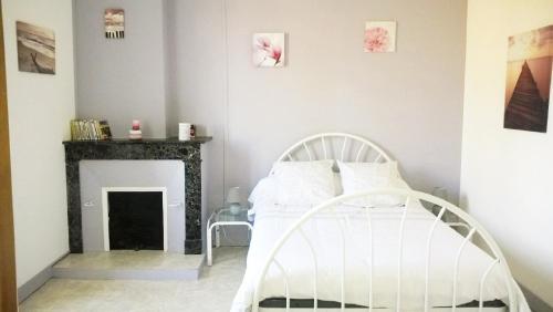 1 dormitorio con cama blanca y chimenea en LOCATIONS RIVES DE SEUGNE - De Gaulle, en Jonzac