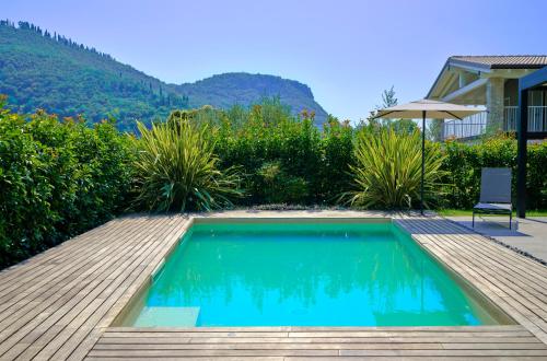 una piscina con terraza y una silla junto a una casa en ApartmentsGarda - Aurora Deluxe, en Garda