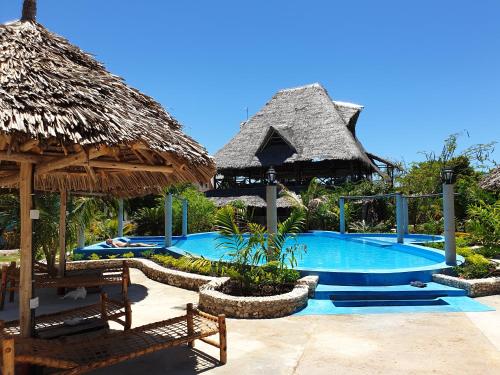 a resort with a swimming pool and a thatch roof at Jua Peponi in Michamvi