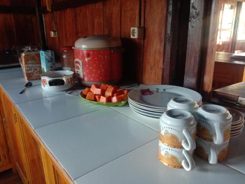 a kitchen counter with a table with plates and fruit at Home stay wolokoro ecotourism in Bajawa