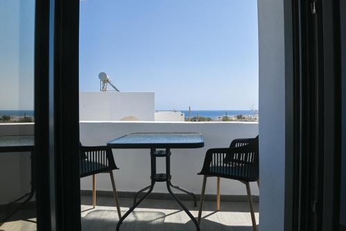 una mesa y sillas en un balcón con vistas al océano en Villa Eleana, en Monolithos