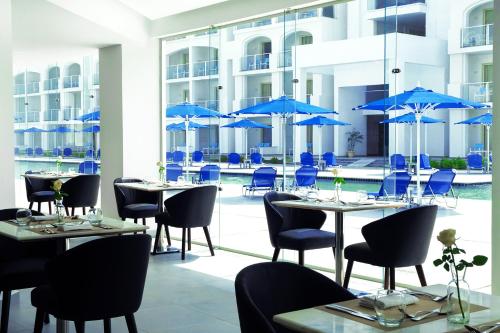 a restaurant with tables and chairs and blue umbrellas at Pickalbatros Blu Spa Resort - Adults Friendly 16 Years Plus- Ultra All-Inclusive in Hurghada