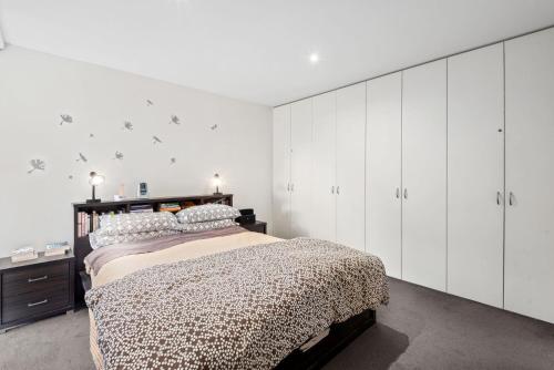 - une chambre avec un lit et des armoires blanches dans l'établissement Spindrift, à Point Lonsdale
