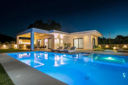 a large swimming pool in front of a house at night at Ocean Pearl Sea View in Faliraki