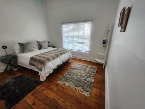 a bedroom with a bed and a window and wooden floors at The Quince & Olive in Parys