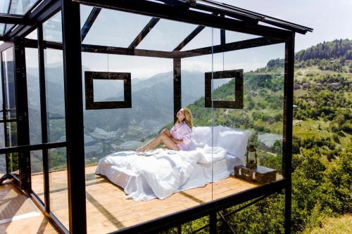 a woman sitting on a bed in a room with a view at Nika Hotel and Club in Chʼanchʼkhalo