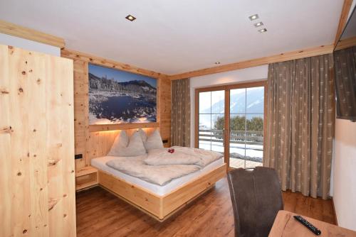 - une chambre avec un lit et une grande fenêtre dans l'établissement Krölls Alpenchalet, à Krimml