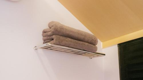 a pile of towels on a towel rack on a wall at Bobocabin Pangalengan, Bandung in Pengalengan