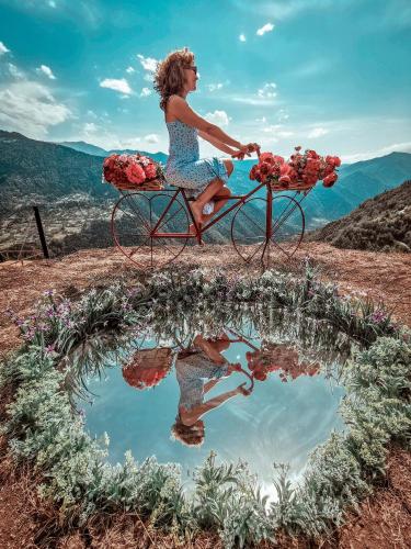 a woman sitting on a bike with a reflection in a puddle at Nika Hotel and Club in Chʼanchʼkhalo