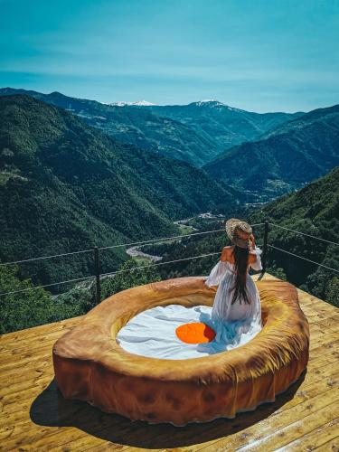 a woman sitting in a large wooden circle in the mountains at Nika Hotel and Club in Chʼanchʼkhalo