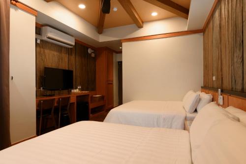 a hotel room with two beds and a flat screen tv at Gaodiyuan Tea B&B 高帝園茶業民宿 in Meishan