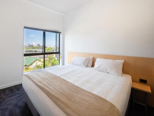 a bedroom with a large bed with a large window at YHA Brisbane City in Brisbane