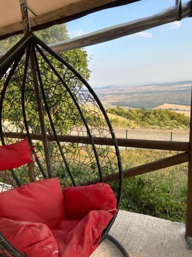 a chair with red pillows sitting on a porch at Хижа Тополица -The beautiful view in Aytos