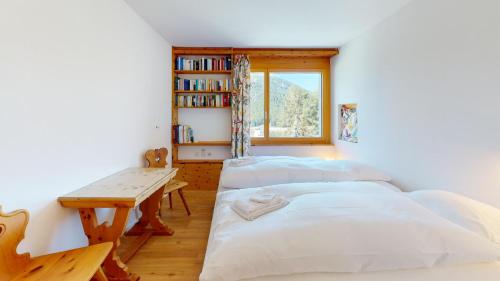 duas camas num quarto com uma mesa e uma janela em Ers 52 em Pontresina
