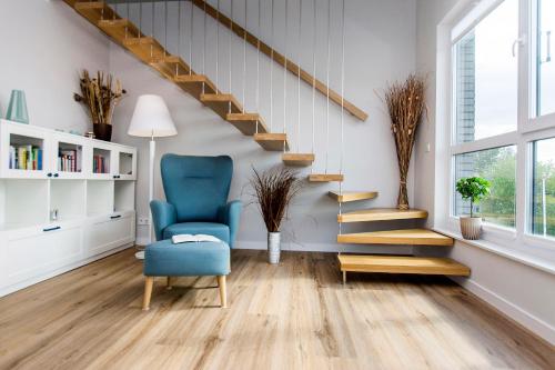 ein Wohnzimmer mit einem blauen Stuhl und einer Treppe in der Unterkunft Villa Neptun - Exclusive Apartments in Danzig