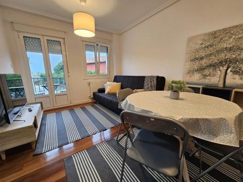uma sala de estar com uma mesa e um sofá em C12A01 Coqueto apartamento con piscina y garaje em Suances