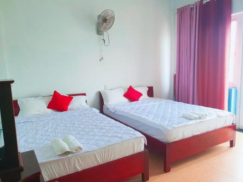 a bedroom with two beds with red pillows and a fan at Thanh Tran Guesthouse Lý Sơn in Ly Son