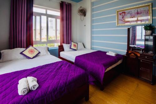 two beds in a room with purple sheets and a tv at Thanh Tran Guesthouse Lý Sơn in Ly Son