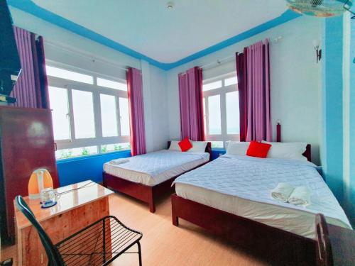 two beds in a room with blue walls and windows at Thanh Tran Guesthouse Lý Sơn in Ly Son