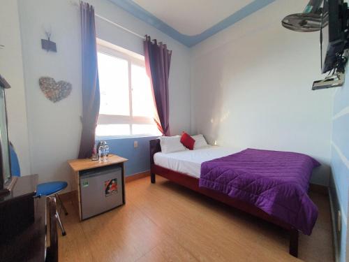a bedroom with a purple bed and a window at Thanh Tran Guesthouse Lý Sơn in Ly Son