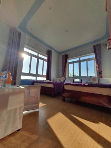 a large bedroom with two beds and windows at Thanh Tran Guesthouse Lý Sơn in Ly Son