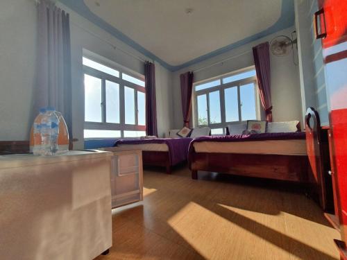 a bedroom with two beds and two windows at Thanh Tran Guesthouse Lý Sơn in Ly Son