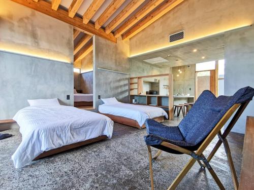 a bedroom with two beds and a blue chair at Amami 与庵 in Amami