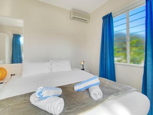 a bedroom with a bed with blue curtains and towels at Picnic Bay Apartments Unit 3 in Picnic Bay