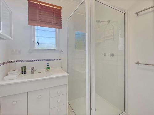 a white bathroom with a shower and a sink at Picnic Bay Apartments Unit 3 in Picnic Bay