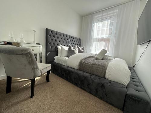 1 dormitorio con 1 cama, 1 silla y 1 ventana en The smaller new refurbished room 5 min from beach/parking in Guests house. en Bournemouth