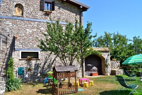 a stone building with a yard with tables and chairs at Mimosa in Hilly area - Happy Rentals in Gargnano