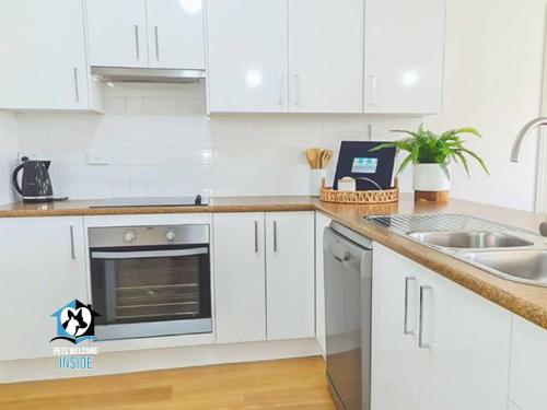a white kitchen with white cabinets and a sink at Coastal Vibe, 4 beds Short Walk to the Beach in Aldinga Beach