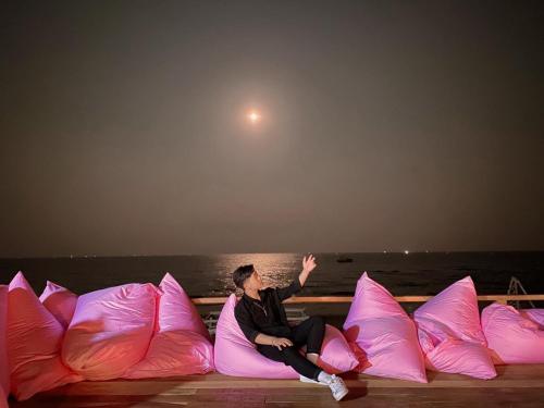a woman sitting on a row of pink pillows at Suly's Village Phan Thiết in Phan Thiet