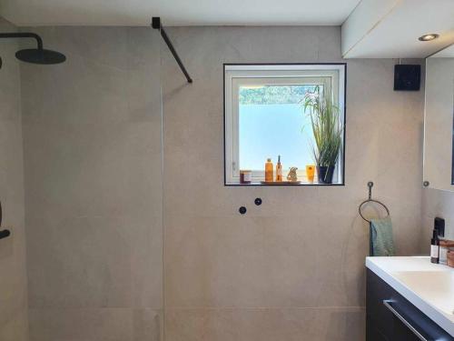 a bathroom with a shower with a window and a sink at Hjemmekoselig fritidsbolig i Andebu på to plan in Andebu