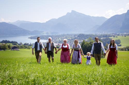 a family walking in a field with mountains in the background at Panorama Hotel Gasthof Leidingerhof in Mondsee
