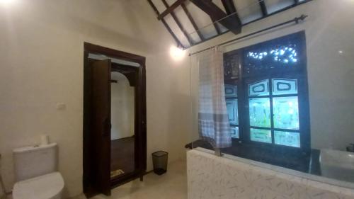 a bathroom with a toilet and a window and a sink at Rumah Jepun in Mataram
