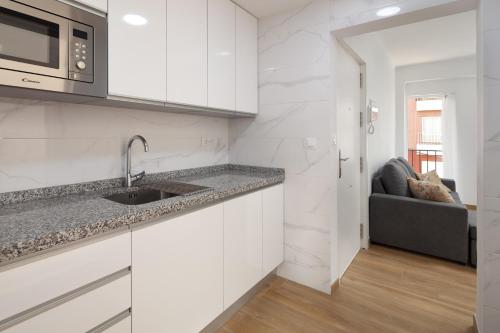 a white kitchen with a sink and a microwave at Apartamento Torre del Mar in Torre del Mar