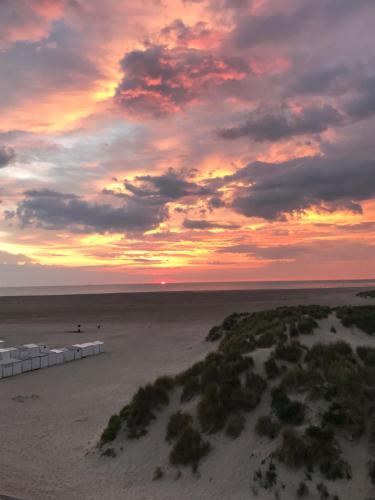 a sunset on a beach with the ocean at DUNE DU PALACE in Zeebrugge