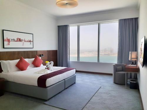 a hotel room with a bed and a large window at Somerset West Bay Doha in Doha