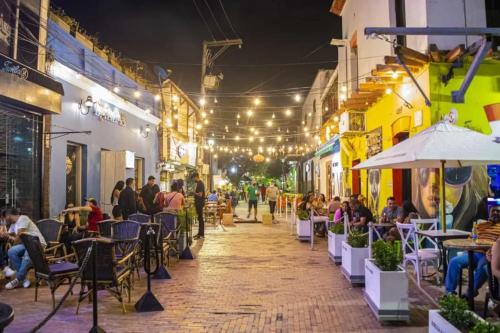 a group of people sitting at tables on a street at night at Aurelia Compartida Hospedaje 2025 in Santa Marta