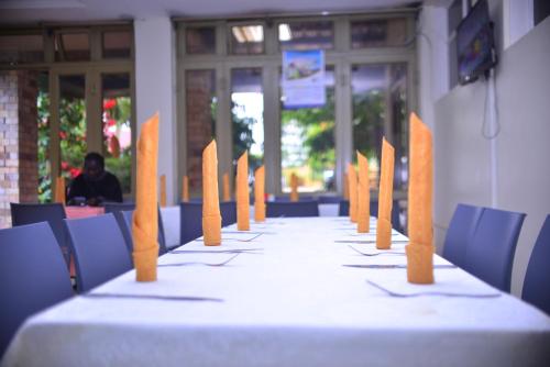 una mesa larga con mantel blanco y sillas azules en Elgon Palace Hotel - Mbale, en Mbale