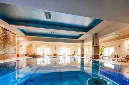 a large swimming pool with a blue ceiling at Dosłońce Resort Wellness & Farm in Racławice