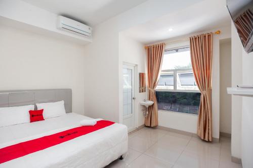 1 dormitorio con cama blanca y ventana en RedDoorz @ Kali Balok Lampung, en Geruntang
