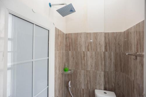 a bathroom with a toilet and a glass shower at RedDoorz @ Kali Balok Lampung in Geruntang