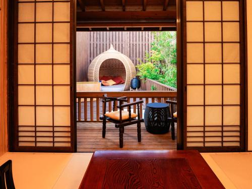 a room with a balcony with a table and a chair at AsoTsuruya in Aso